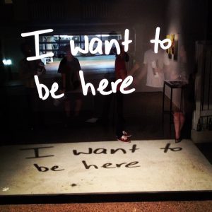'I want to be here' 2014, vinyl text on glass window with spot light.