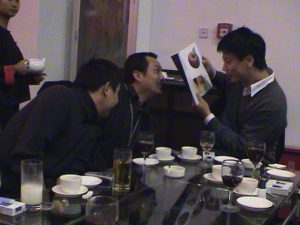 Curator PiLi, with artists Wang Gongxin and Zhu Jia looking at the 'MAAP in Beijing' catalogue at the after opening dinner celebration. October 2002
